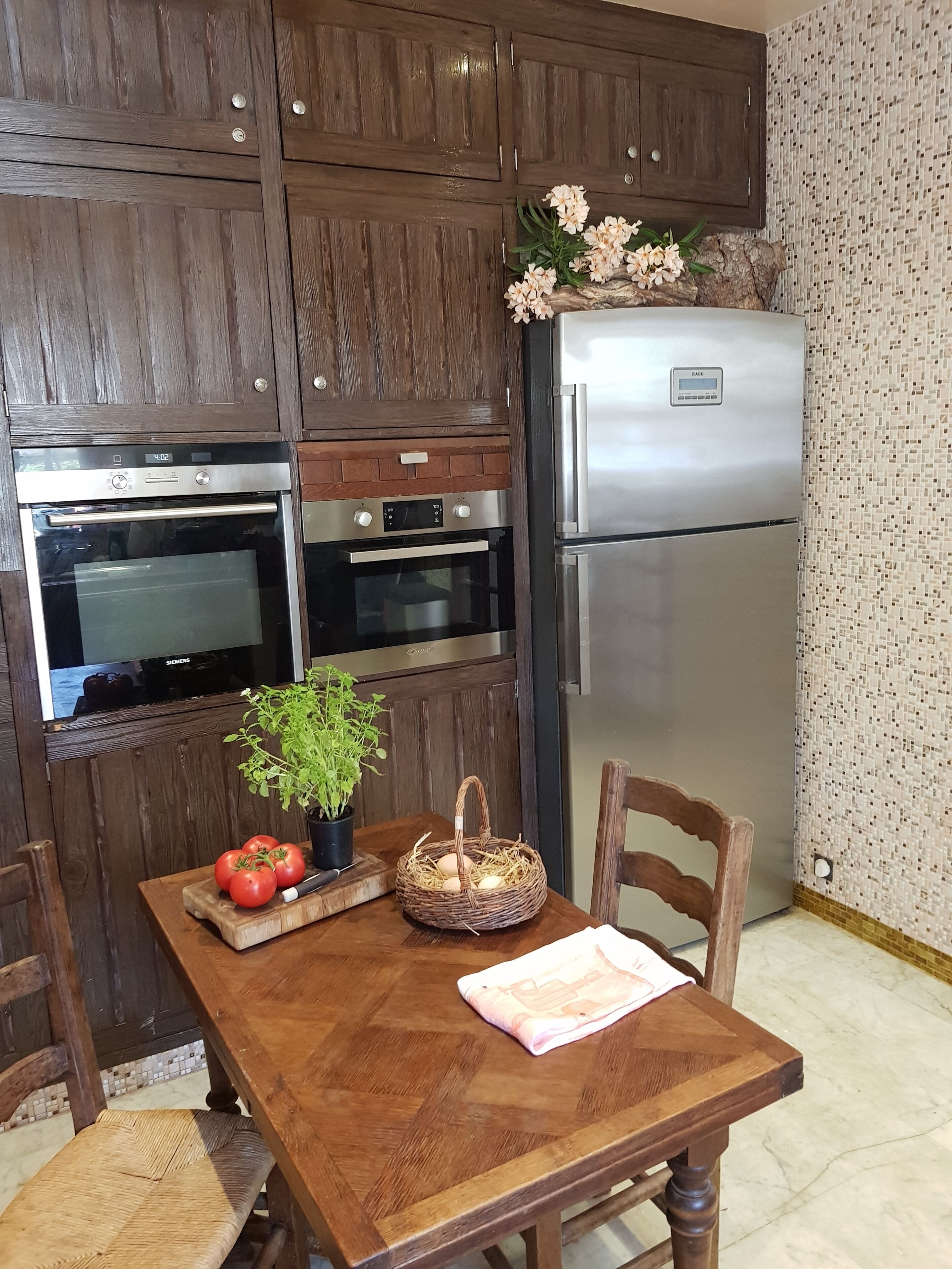 Una cocina con armarios de madera, un refrigerador de acero inoxidable y una mesa de comedor con sillas.