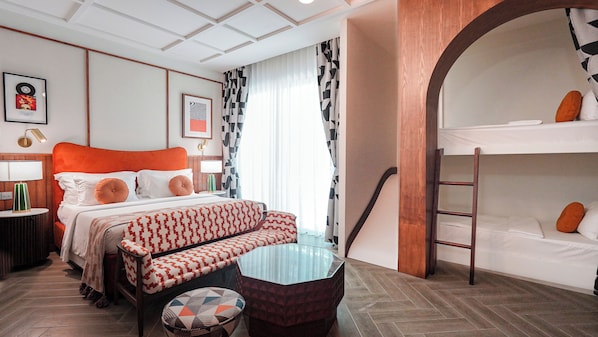 Une chambre d’hôtel avec un lit, un canapé, une petite table, une échelle et un lit superposé.