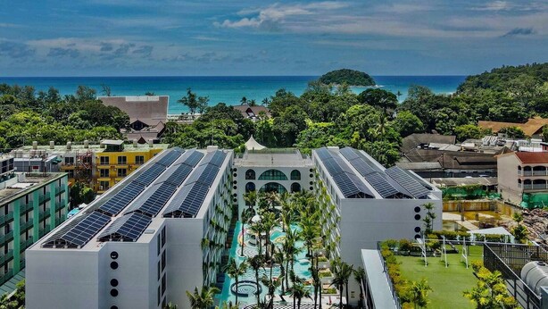 Un hôtel à plusieurs étages, doté de panneaux solaires sur le toit, d’une piscine et offrant une vue sur l’océan.