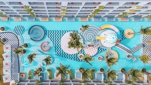 Un espace piscine doté de plusieurs chaises longues, de transats et de palmiers.