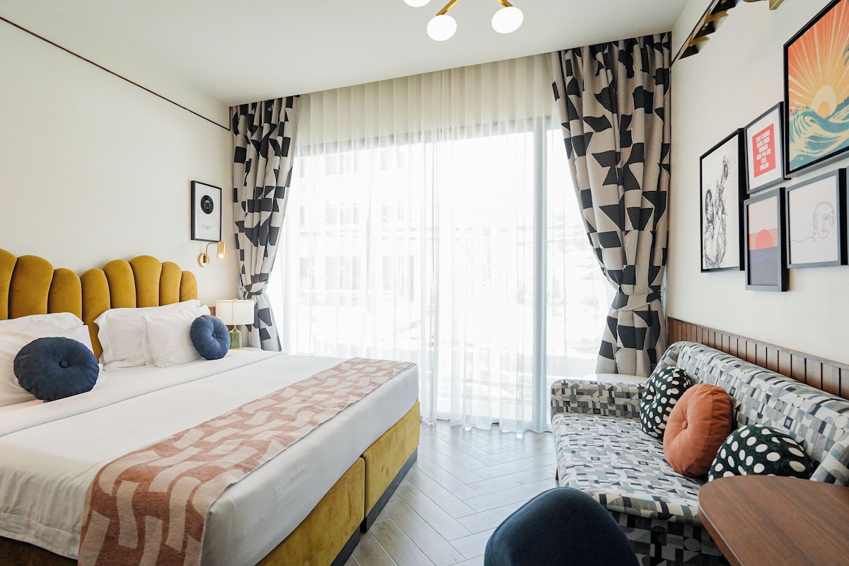 Quarto de hotel com uma cama grande, um sofá e uma mesa de jantar.