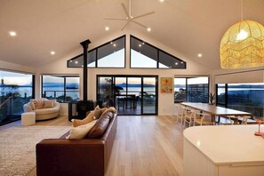 Amplia sala de estar con un ventanal, ventilador de techo y zona de comedor con mesa y sillas.