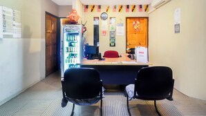A reception area with a desk, two chairs, a clock, and a refrigerator. - OYO 44017 L & C Premium Stay  (Kuching)