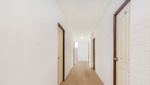 A corridor with doors on both sides, a tiled wall on the right, and a patterned floor. - OYO 44017 L & C Premium Stay  (Kuching)