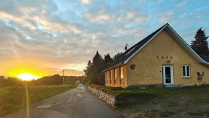 En etagers bygning med en stensokkel og et skråt tag, med en lille veranda og en dør med tallet '1998' på muren.