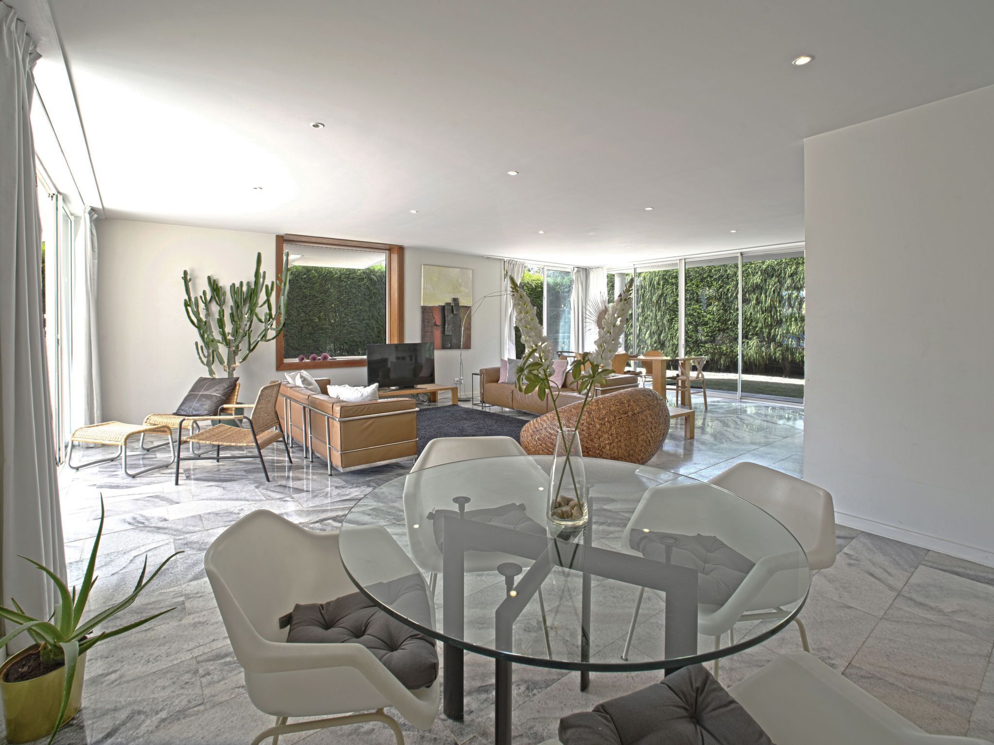 A modern living room with a large TV, comfortable seating, and a glass table.