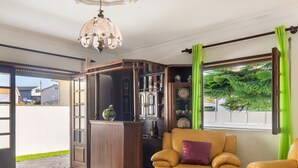 Una sala de estar con un sofá amarillo, un aparador de vidrio y vistas al exterior.