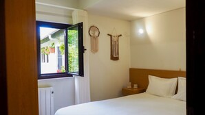 A bedroom with a bed, a nightstand, a wall-mounted macrame decoration, and a window with curtains. - Vacation home Lopes by Interhome (Fao)