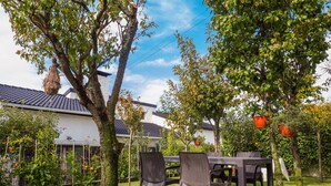 A patio with a table and chairs, surrounded by trees and a white building with a tiled roof. - Vacation home Lopes by Interhome (Fao)