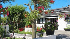 A white building with a tiled roof, surrounded by potted plants and flowers. - Vacation home Lopes by Interhome (Fao)