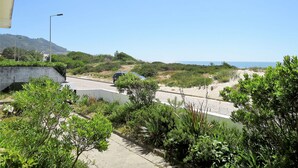 Eine Küstenstraße mit Blick auf das Meer, umgeben von Grünpflanzen und einer Betonbarriere.