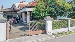 Une maison d’habitation avec un toit en tuiles, une allée bordée de portails et un arbre devant.
