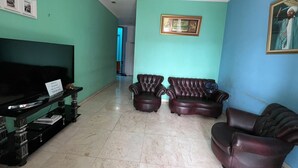 A living room with teal walls, a ceiling with a recessed design, two leather sofas, a black entertainment unit, and a framed picture on the wall.