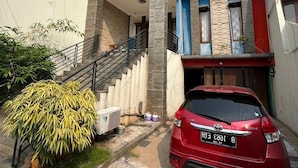 A modern two-story house with a red car parked in front.