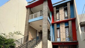 A two-story building with a balcony on the upper floor, a staircase leading to the entrance, and a red and blue facade.