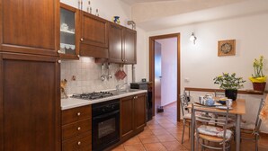 Une cuisine avec des meubles de rangement en bois, une cuisinière et un coin repas comprenant des chaises et une table.