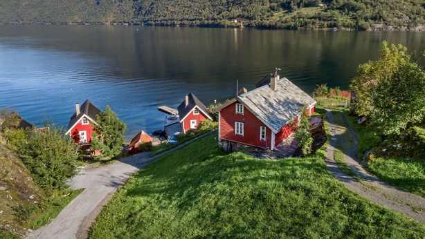 Uma vila à beira do lago com casas tradicionais vermelhas, vista clara do lago e uma montanha ao fundo.