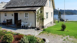 A two-story house with a tiled roof, a front porch with chairs, and a view of a lake and mountains.