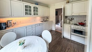 A kitchen with white cabinets, a dining table with chairs, and a staircase leading to another room.