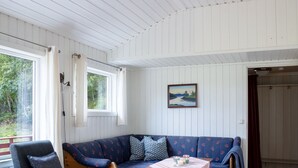 A cozy room with a blue sofa, a wooden table, and a view of greenery outside. - Fjordglytt by Interhome (Onarheim)