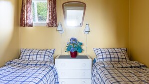 A bedroom with two beds, a dresser, a window with curtains, a mirror, and a potted plant. - Fjordglytt by Interhome (Onarheim)