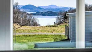 Une vue depuis une fenêtre donnant sur un lac, avec des montagnes en arrière-plan.