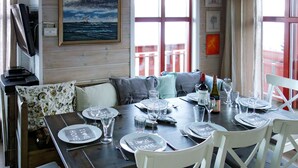 A dining area with a wooden table set for four, white chairs, and a bench. - Elistova by Interhome (Onarheim)