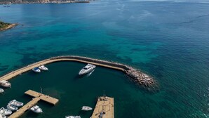 Un port de plaisance avec des bateaux amarrés, une jetée et une chaîne de montagnes en arrière-plan.