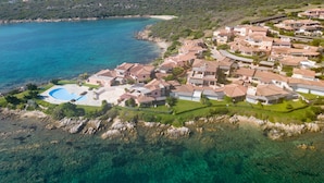 An aerial view of a coastal residential area with houses, a clear blue sea, and a swimming pool. - Apartment Timo by Interhome (Golfo Aranci)