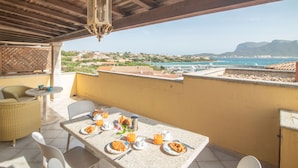 A terrace with a table set for breakfast, overlooking a coastal town and the sea. - Apartment Timo by Interhome (Golfo Aranci)