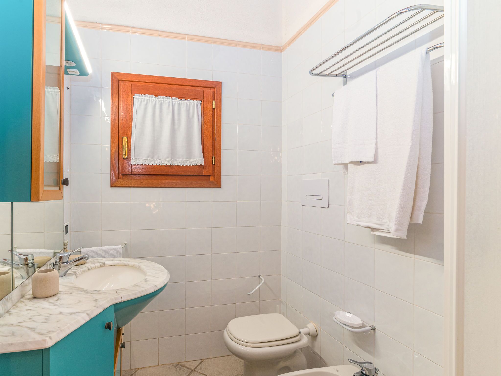 Ein Badezimmer mit Waschbecken, Spiegel, Toilette und Handtuchhalter.