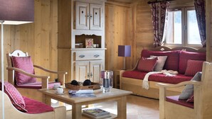 L’intérieur d’un chalet en bois chaleureux et accueillant, avec un canapé, des fauteuils, une table et un buffet.