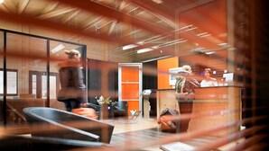 Un intérieur moderne comprenant un comptoir d’accueil, un espace détente et une grande fenêtre.