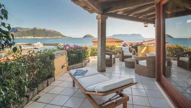 A covered outdoor seating area with wicker furniture and a view of the sea. - Eucalipto by Interhome (Golfo Aranci)