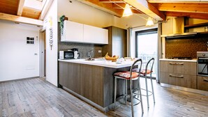 Una cocina moderna con vigas de madera, una isla central, taburetes de bar y vistas al exterior.