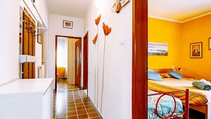 Un pasillo que conduce a un dormitorio con una cama, un radiador y una puerta.