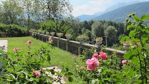 Un jardin agrémenté d’une balustrade en pierre, d’une végétation luxuriante et de fleurs roses.