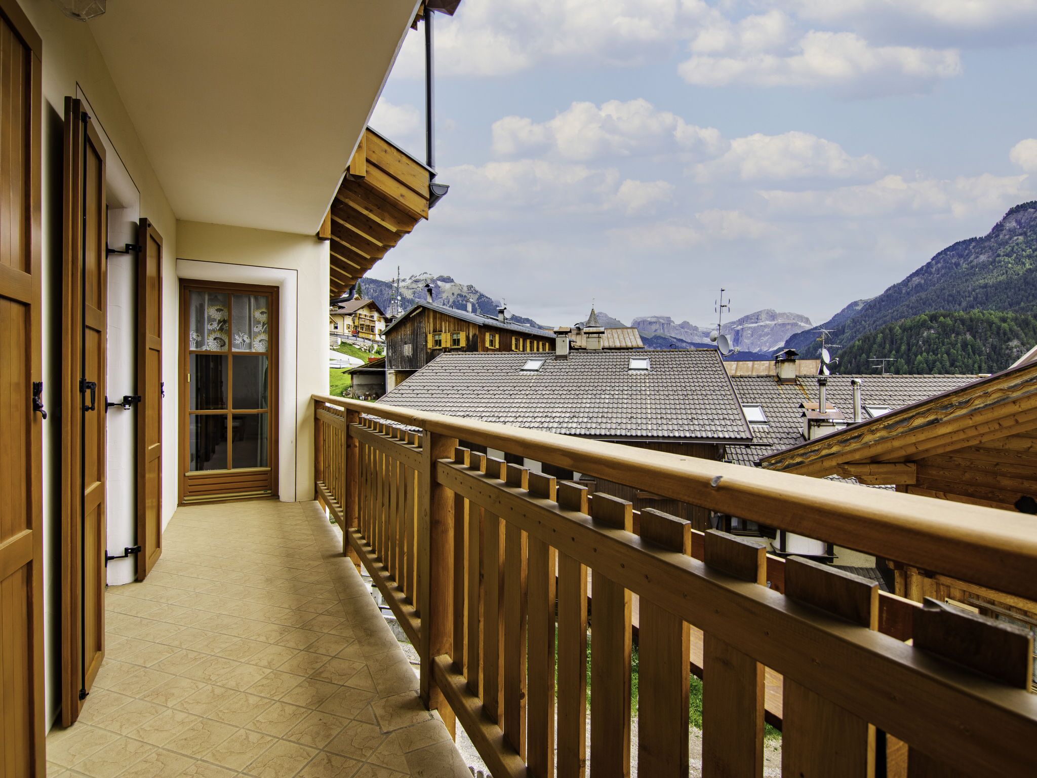 A wooden balcony with a view of traditional mountain buildings and a mountainous landscape.