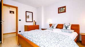 A bedroom with a wooden bed, a nightstand, a dresser, a mirror, and a wall-mounted picture. - Stabler by Interhome (Pozza di Fassa)