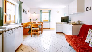 A compact living space with a kitchen, dining area, and a red sofa. - Stabler by Interhome (Pozza di Fassa)