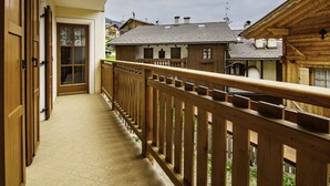 Un balcón de madera con piso de baldosas, con vista a una hilera de casas tradicionales con techos inclinados.