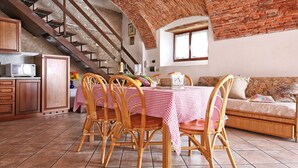 A dining area with a checkered tablecloth, wicker chairs, a brick ceiling, and a staircase. - Il Colombaro by Interhome (Salo')