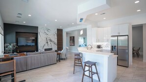 A modern kitchen with a central island, built-in appliances, and a dining area with a sofa and chairs. - Palm Luxe Estate: Luxury Desert Retreat Pool & Spa (Indio)