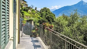 A balcony with a stone wall, potted plants, and a view of a mountain. - Casa Bel Sit by Interhome (Acquaseria)