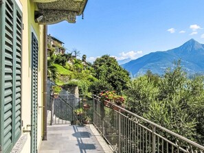 Un balcone con un muro in pietra, piante in vaso e vista su una montagna.