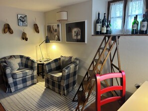 A living room with two plaid sofas, a red chair, a wooden ladder, and a wine rack with bottles. - B&B Borgolecchi (Gaiole in Chianti)