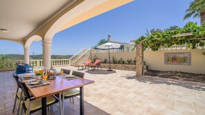 A covered patio with a table set for dining, outdoor seating, and a view of the landscape. - Quinta do Mosaico by Interhome (Lagos)