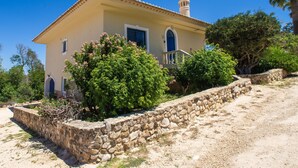 A two-story house with a stone retaining wall, a balcony, and a clear blue sky. - Quinta do Mosaico by Interhome (Lagos)