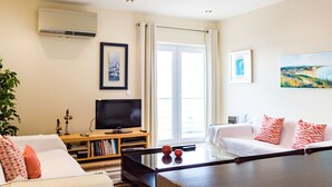 Een moderne woonkamer met een flatscreen televisie, een boekenkast, een bank en een schilderij aan de muur.