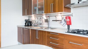 Een moderne keuken met houten kastjes, roestvrijstalen apparatuur en een gasfornuis.
